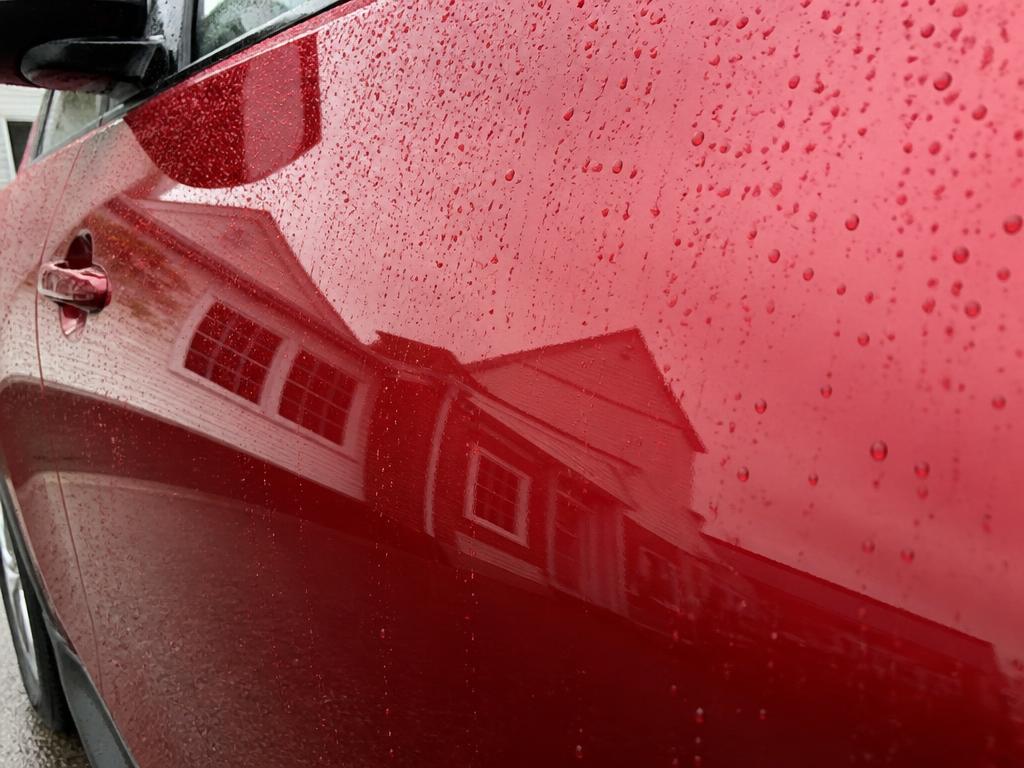 Close-up of a freshly polished deep red paint panel with mirror gloss